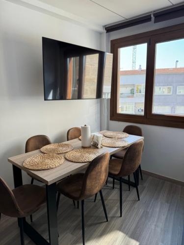a dining room table with chairs and a television at Vellosol in Vigo