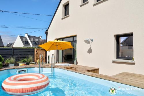 une piscine avec un parasol et une balle rouge et blanche dans l'établissement 4 minutes à pieds de la plage., au Conquet