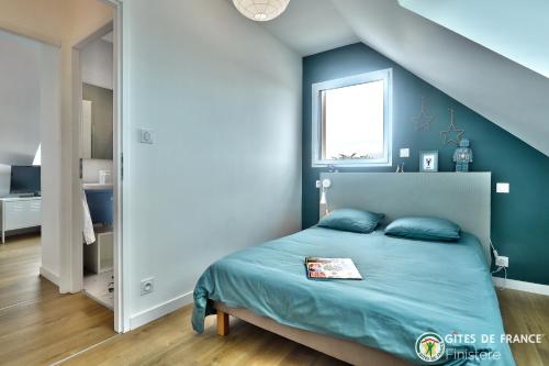 une chambre avec un lit avec un mur bleu dans l'établissement 4 minutes à pieds de la plage., au Conquet