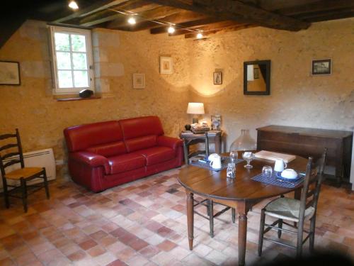 un salon avec un canapé rouge et une table dans l'établissement Gîte Bois Gaillard, à La Flèche