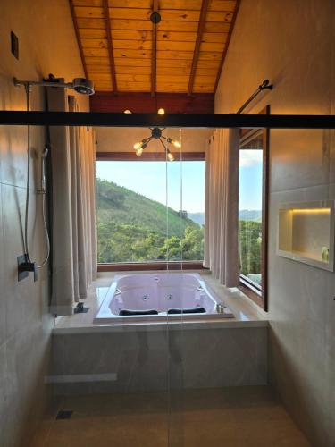 a large bath tub in a bathroom with a window at POUSADA QUINTAL DAS OLIVEIRAS in Monte Verde
