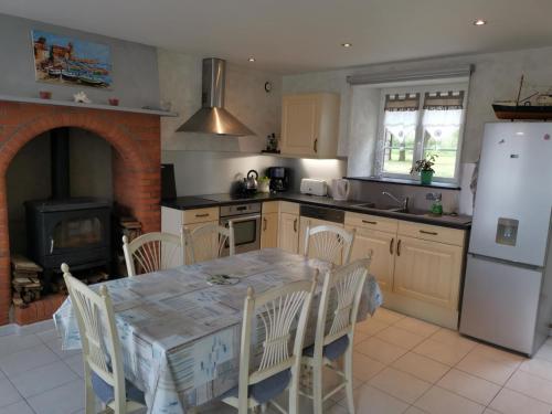 La cuisine est équipée d'une table, d'une cuisinière et d'un réfrigérateur. dans l'établissement Maison au bord de la mer, à Bretteville-sur-Ay