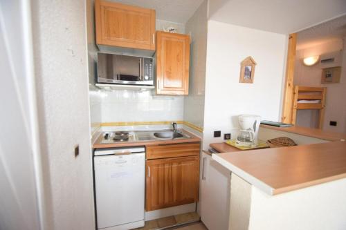 Elle comprend une petite cuisine avec des placards en bois et un évier. dans l'établissement Résidence Le Squaw Valley - Studio cabine 3/4 pers - LE SQUAW VALLEY - PLAGNE VILLAGES MAE-1544, à Aime La Plagne