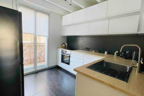 une cuisine avec des armoires blanches et un évier dans l'établissement Magnifique appartement dans l'hypercentre, à Nantes