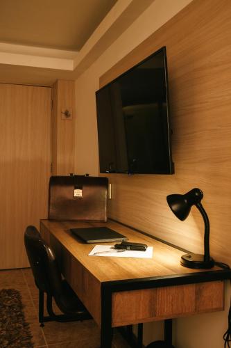 a desk with a lamp and a television on a wall at drb Suites in Cali