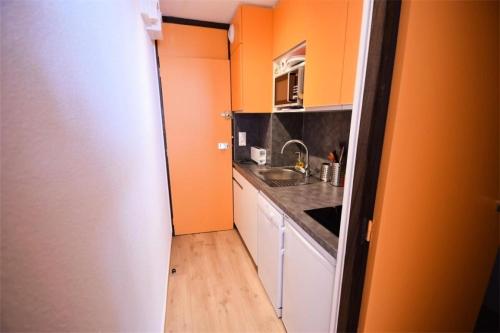 - une petite cuisine avec des murs orange et un évier dans l'établissement Résidence Le France - Studio 2 pers LE FRANCE - PLAGNE CENTRE MAE-9334, à Aime La Plagne