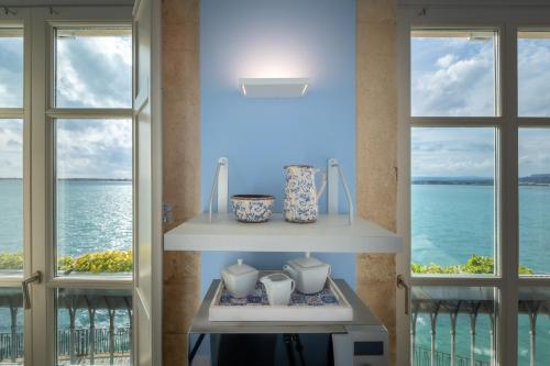 a room with two windows with a view of the ocean at Palazzo Alfeo Aparthotel in Siracusa