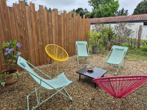 three chairs and a table in a yard with a fence at Maison au coeur d’Arcangues, proximité de Biarritz in Arcangues