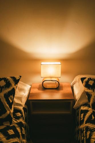 a lamp sitting on a table next to two beds at drb Suites in Cali