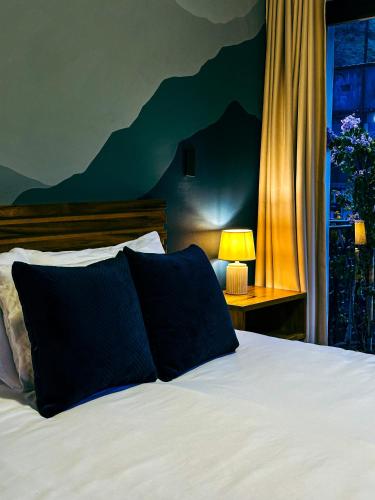 a bedroom with a bed with a black pillow and a window at Hotel Agave Baños in Baños