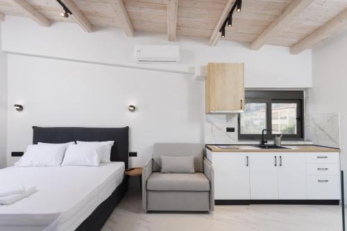 a bedroom with a bed and a chair and a kitchen at Rigas Boutique Rooms in Pefkochori