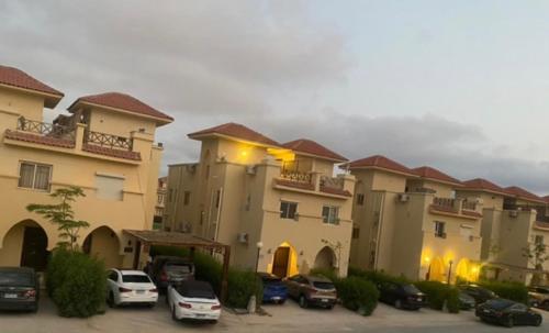 a group of buildings with cars parked in a parking lot at Villa in Stella Heights - North Coast in El Alamein