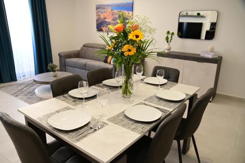 a table with chairs and a vase of flowers on it at Mellieha Centre Melmar Apartment in Mellieħa