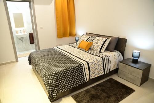 a bedroom with a bed with a black and white comforter at Mellieha Centre Melmar Apartment in Mellieħa