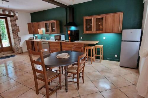une cuisine avec une table, des chaises et un réfrigérateur dans l'établissement La Sérénité des Arbres, à Flavacourt