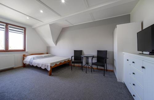 a bedroom with a bed and a table and chairs at Pensjonat Basia in Dziwnówek
