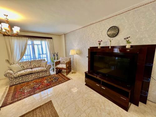 Una sala de estar con un sofá y un televisor. en Luxurious 3 BR Rustic Apartment Overlooking Huge Garden - For Families and Couples, en El Cairo