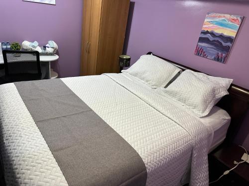 a bedroom with a white bed with a purple wall at Serenity & memorable Cozy Lower Level Apartment Room in TownHouse Private Entrance in Gatineau