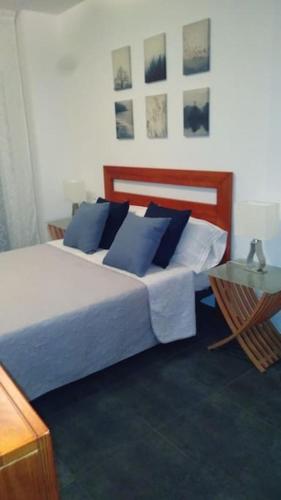 a bedroom with a bed with blue pillows and a table at Piso Encanto Palmeiro in Jove