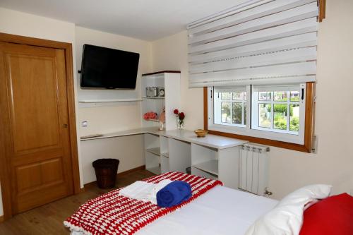 a bedroom with a bed with a desk and a television at Casa familiar cerca de playa América in Nigrán
