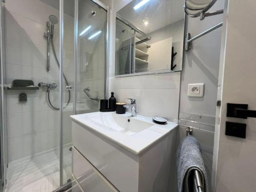 une salle de bain blanche avec un lavabo et une douche dans l'établissement Parisian Charm Close Trocadero, à Paris