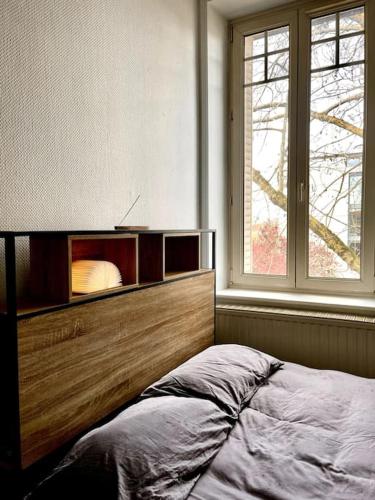 une chambre avec une grande tête de lit en bois et une fenêtre dans l'établissement Charmant appart proche Stanislas, à Nancy