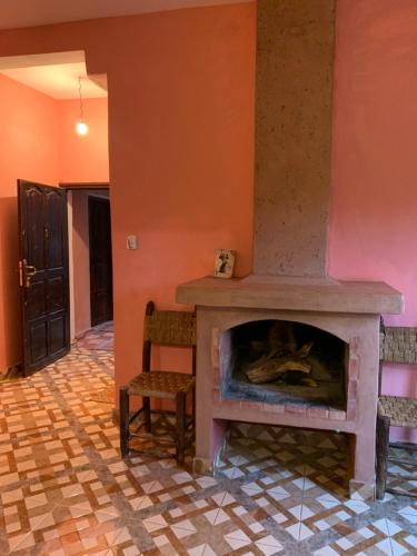 a living room with a fireplace and two chairs at Auberge Le Mouflon in Ouirgane