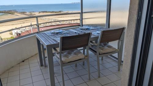 une table et des chaises sur un balcon avec vue sur la plage dans l'établissement KerLorandeEvens, face mer, parking, à Pornichet