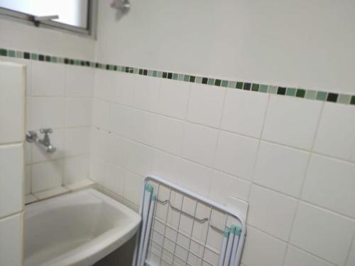 a white tiled bathroom with a sink and a tub at Apto no Bairro Alto Umuarama in Uberlândia