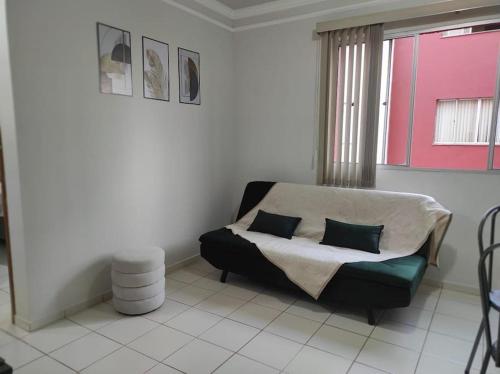 a living room with a couch and a window at Apto no Bairro Alto Umuarama in Uberlândia