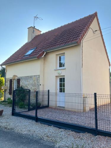a house with a fence in front of it at Gîte des champs fondus in Picauville