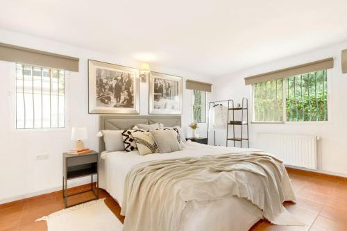 a white bedroom with a large bed and windows at Elviria Beachside House Marbella in Marbella