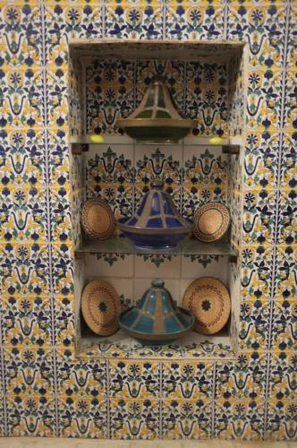 a shelf with bowls and vases on a wall at Belle maison dans la Médina in Tunis