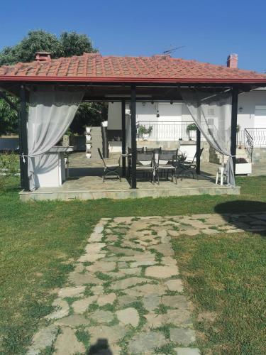 a pavilion with a table and benches in a yard at Villa Adamidis in Paralía Skotínis