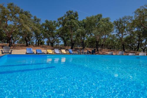 a swimming pool with chairs and trees in the background at Valle D`Água - Casas de campo in Vale de Água
