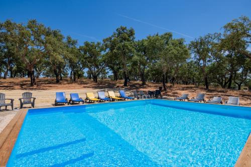 a swimming pool with chairs and trees in the background at Valle D`Água - Casas de campo in Vale de Água