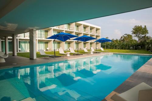 a swimming pool with chairs and umbrellas in front of a building at Hotel Aqua Spa & Resort in Martínez de La Torre