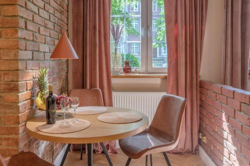 a dining room table with chairs and a brick wall at Amber Apartament in Gdańsk