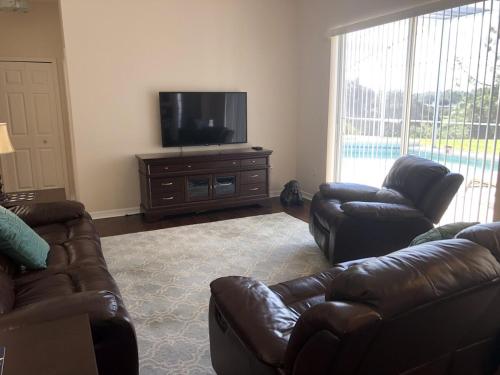a living room with two leather couches and a flat screen tv at Private Large Pool Villa Southern Dunes Golf Views Large Pool Deck in Haines City