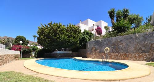 een zwembad in een tuin met een stenen muur bij Las Palmeras del Cantal in Mojácar