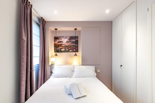une chambre avec un lit blanc et une fenêtre dans l'établissement Appartement Cosy au cœur du Triangle d Or avec Climatisation, à Paris