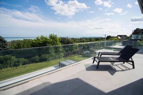 a bench on a balcony with a view of the ocean at Horizont Apartman in Alsóörs