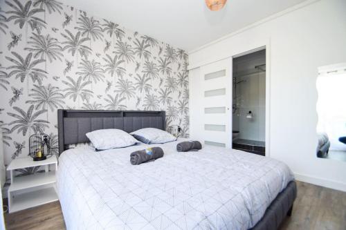 - une chambre avec un grand lit blanc et du papier peint en palmier dans l'établissement Appt 4 pers à 400m plage avec jardin, à Dinard