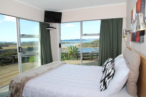 a bedroom with a white bed and a large window at Cook's Lookout Motel in Paihia