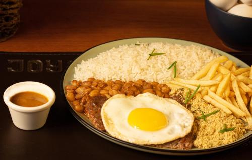 a plate of food with an egg and rice and french fries at Joy Hostel & Suítes in Brasilia
