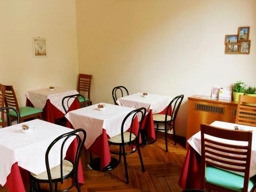 un comedor con mesas blancas y sillas con arcos rojos en Hotel Eden, en Milán