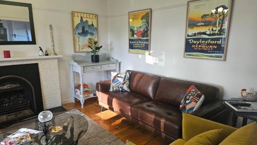 a living room with a leather couch and a fireplace at Sausalito- captivating 1950s retro residence in Daylesford