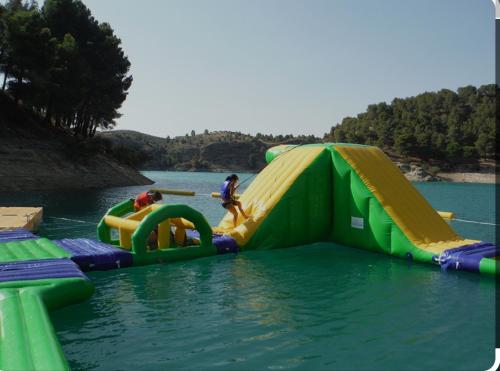 a group of people playing on an inflatable slide in the water at La guarida delChorro in Málaga