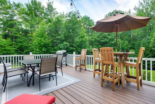 a deck with a table and chairs and an umbrella at 6 Mi to Mt Snow Nature-View Home with Fire Pit! in West Dover