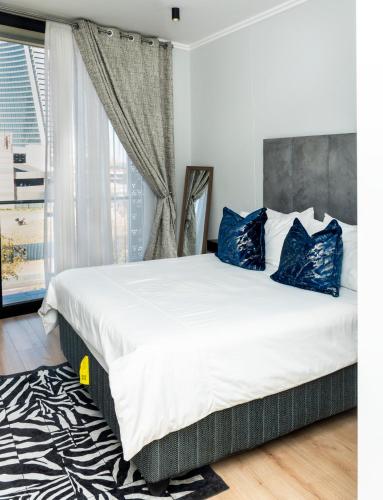 a bedroom with a large bed with blue pillows at Ellipse Waterfall Luxury Apartments in Midrand